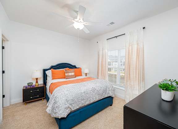 A bedroom with a bed, nightstand, and window.