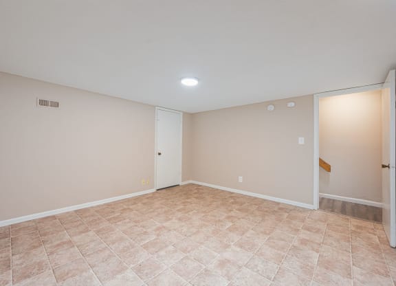an empty living room with beige walls and a tiled floor