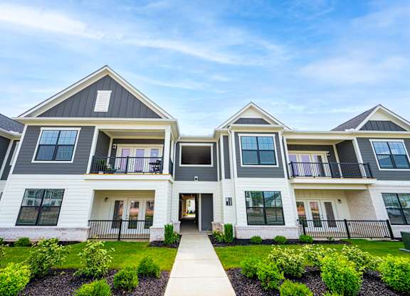 A modern two-story house with a front yard and a clear sky.
