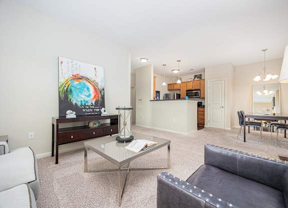 A living room with a grey couch and a glass coffee table.