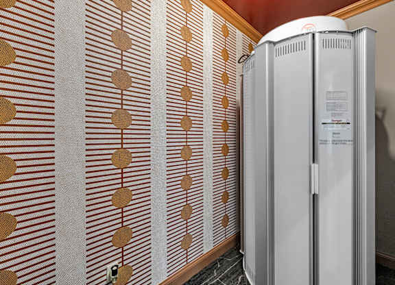 A wall with a brown and white patterned wallpaper and a white fridge.