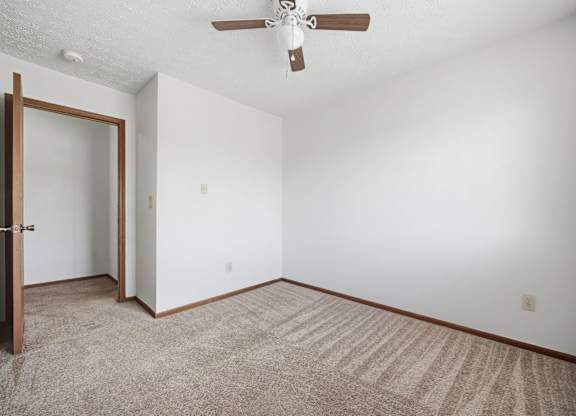 A room with a ceiling fan and carpeted floor.