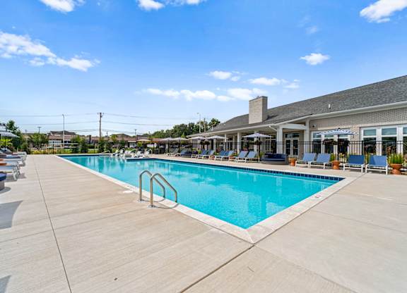 A large outdoor swimming pool with a wooden deck and lounge chairs.