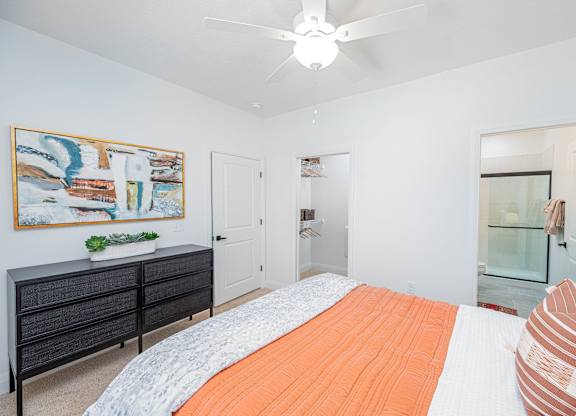 A bedroom with a bed, dresser, and painting on the wall.