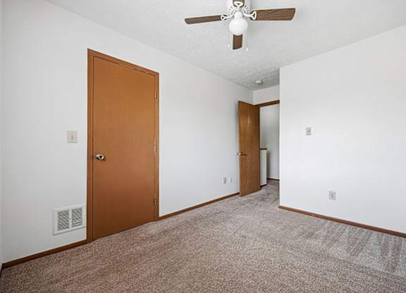 A room with a ceiling fan and two doors.