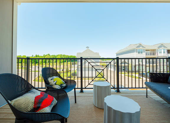 a balcony with chairs and tables and a view of a yard and houses