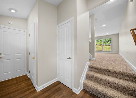 A hallway with a staircase leading to a balcony.