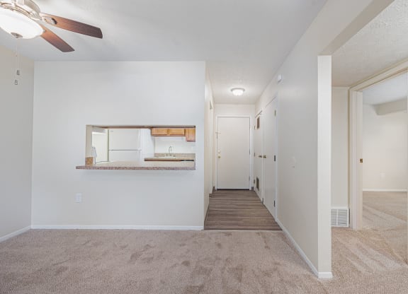 an empty living room and hallway with a ceiling fan
