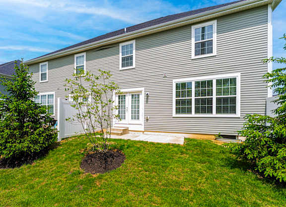 A grey house with a tree in front of it.
