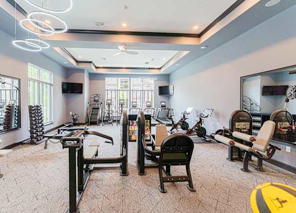 A spacious gym with various exercise equipment and mirrors.