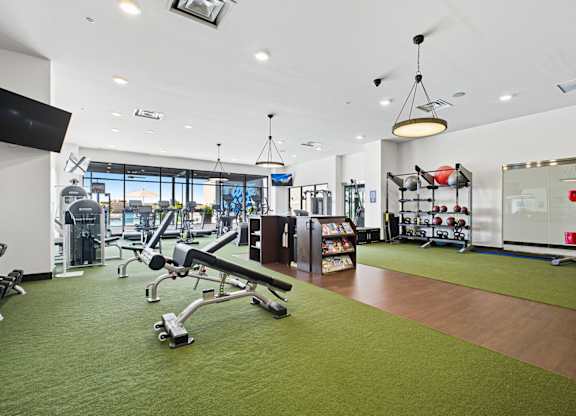A gym with a variety of equipment including treadmills, weights, and exercise machines.