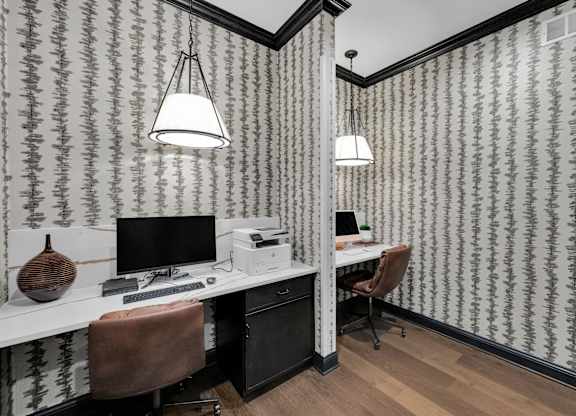 A room with a desk and a chair with a patterned wallpaper.