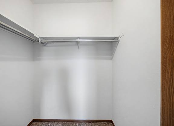 A white wall with a shelf and a brown floor.