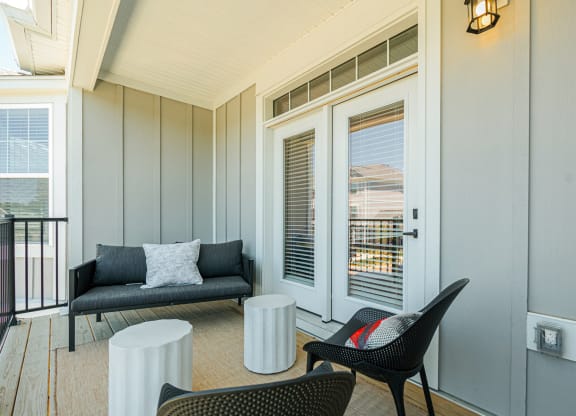 a living room with a couch and chairs and a balcony
