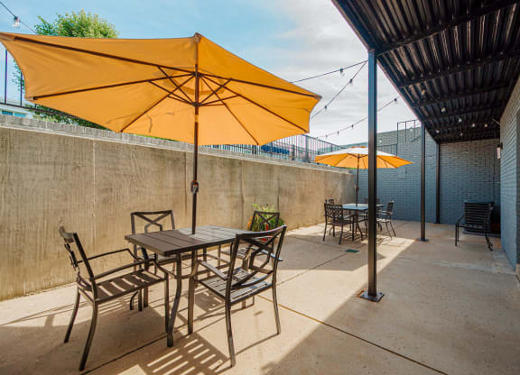 a patio with tables and chairs under umbrellas