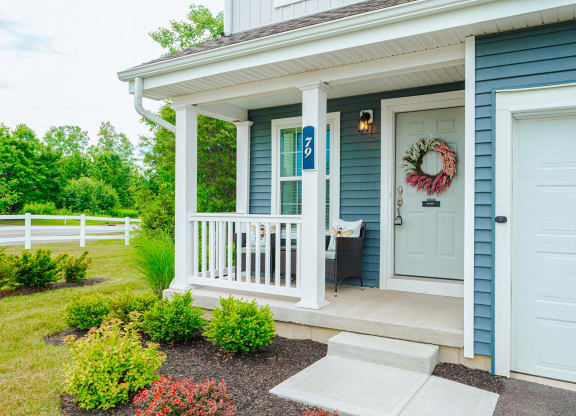 the front porch of a blue house with a white door