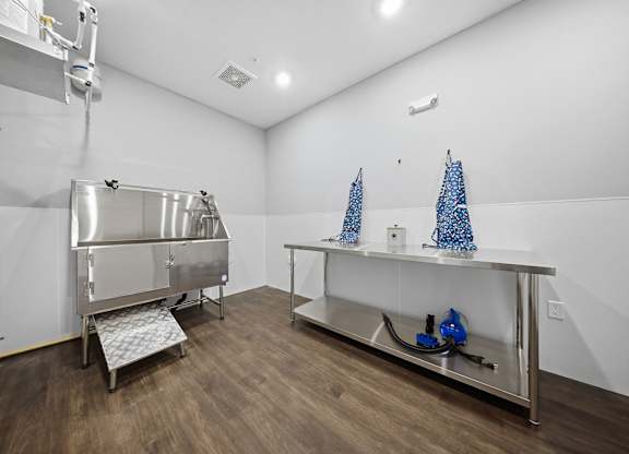 A clean, empty room with a stainless steel sink and a wooden floor.