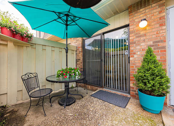 A patio with a table, chairs, and an umbrella.