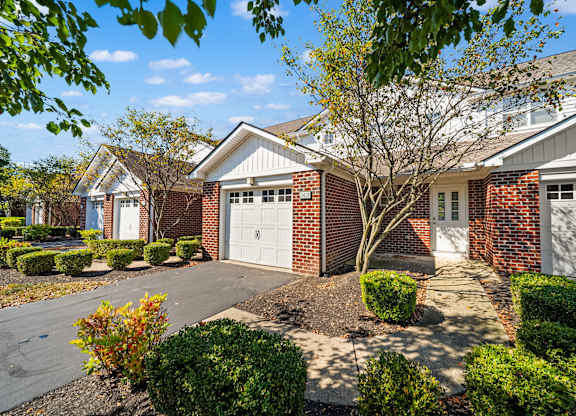 A house with a white garage door is surrounded by a well-manicured garden.
