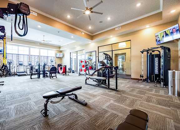 A gym with a variety of equipment including treadmills, weights, and exercise machines.