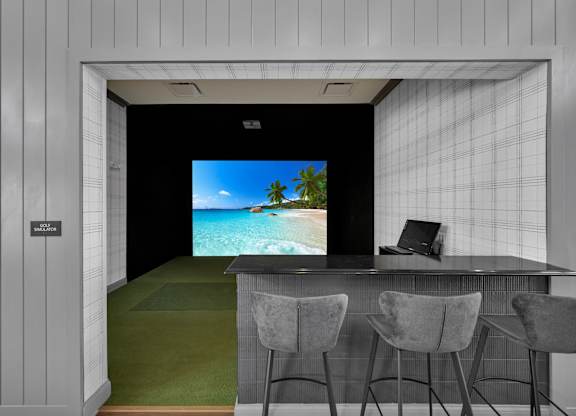 A room with a bar and chairs with a screen on the wall.