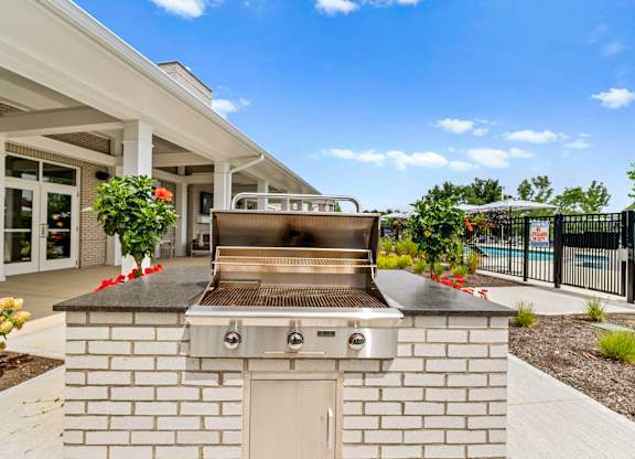 A modern outdoor kitchen with a built-in grill and a white brick exterior.