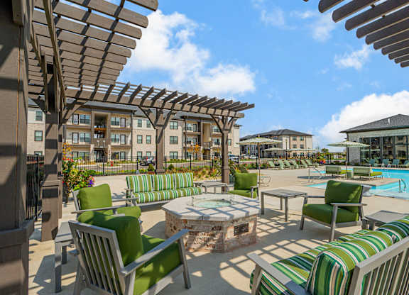 A sunny day at the poolside with green striped chairs and tables.
