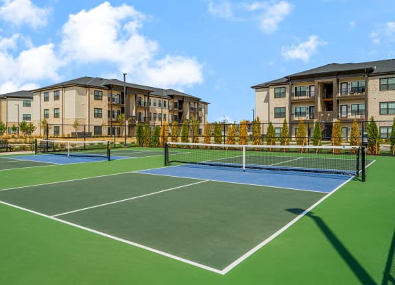 a tennis court with apartments in the background
