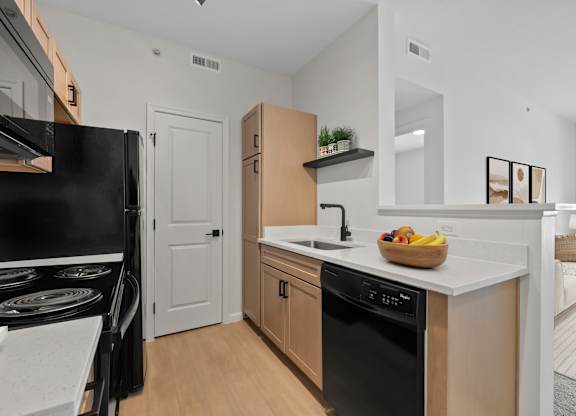 A kitchen with black appliances and wooden cabinets.