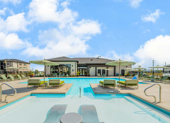 a swimming pool with lounge chairs and a building in the background