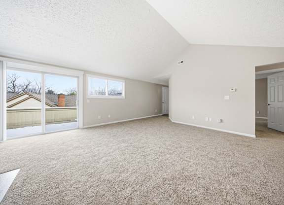 Empty room with carpeted floor and sliding glass doors.