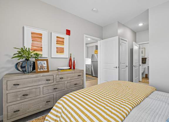 A bedroom with a bed, dresser, and two framed pictures on the wall.