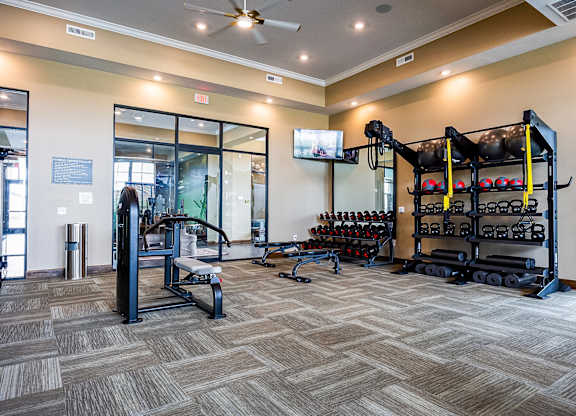 A gym with a variety of equipment including weights and a bench.