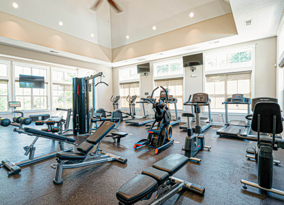 a spacious gym with cardio equipment and windows