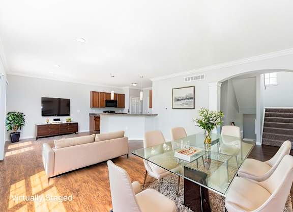 A modern living room with a glass table and white chairs.