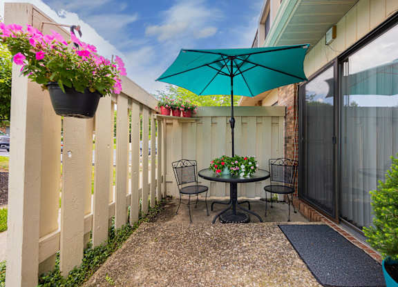 A patio with a table and chairs under an umbrella.