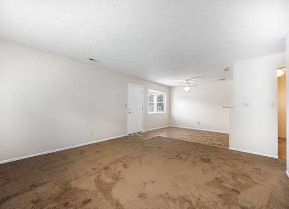 an empty living room with carpet and white walls