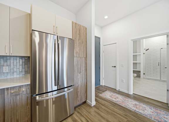 A kitchen with a stainless steel refrigerator and wooden cabinets.