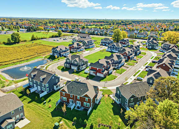 A bird's eye view of a residential neighborhood with houses and a pond.
