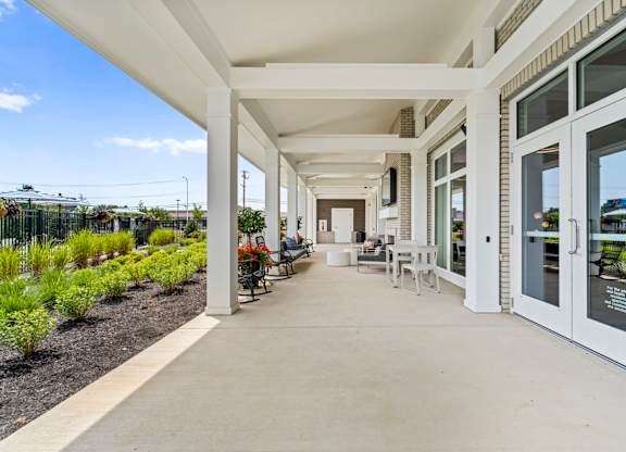 A long white covered walkway with tables and chairs on either side.
