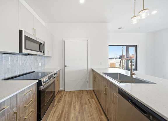 A kitchen with wooden floors and a black counter top.