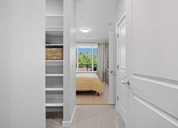 A white hallway with a bedroom at the end.