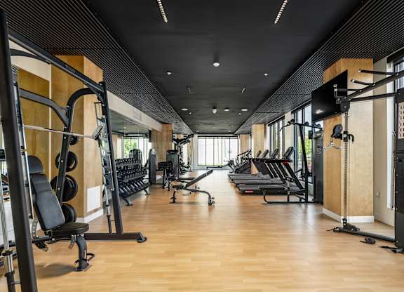 A gym with a variety of equipment including treadmills, weights, and exercise machines.