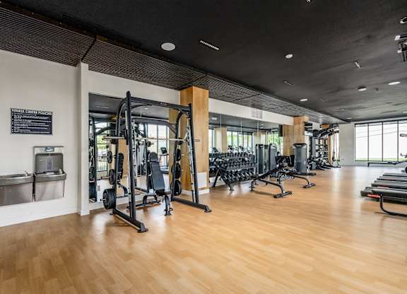 A gym with wooden floors and various exercise equipment.