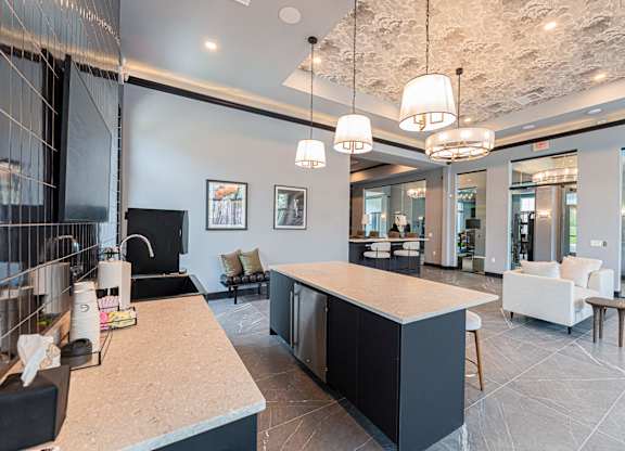 A modern kitchen with a black counter and white chairs.