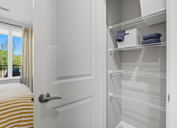 A white, empty, metal shelving unit is in a room with a door.