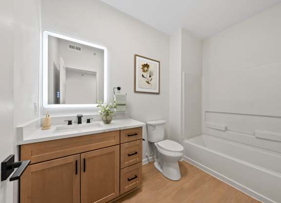 A white bathroom with a wooden vanity and a white toilet.
