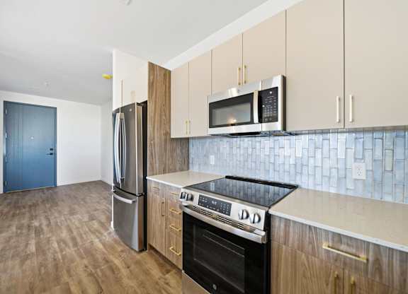 A kitchen with a refrigerator, oven, and microwave.