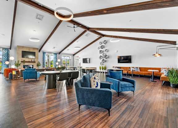 A spacious living room with a dark blue sofa and wooden floors.