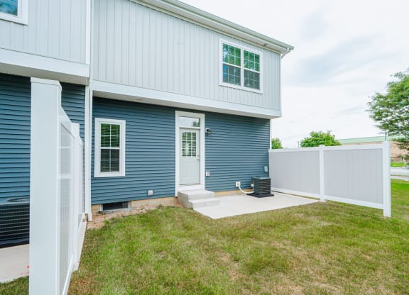 the front door of a blue house with a white fence